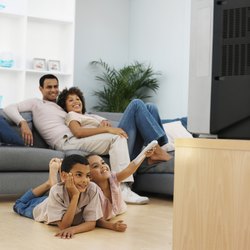 Front view of parents and two children watching television (9-11)