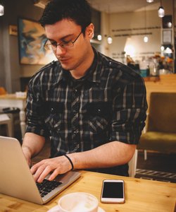 Young man sitting in a coffee shop using laptop