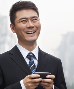 Young Businessman Smiling and Using a Smart Phone