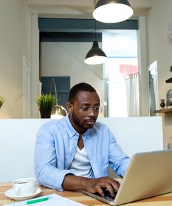 Handsome young black man working with laptop at home.