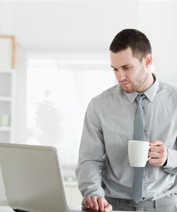 Portrait of a businessman using a notebook while drinking tea