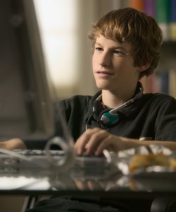 lifestyle portrait of a teenage male as he sits at his computer and works