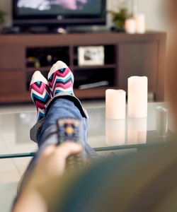 Woman Relax On Sofa Watching Film On TV With Remote