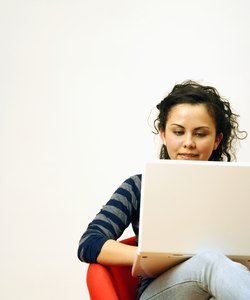 Girl (14-15) using laptop, sitting on chair, smiling