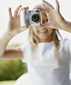 Young Girl Takes a Picture With a Digital Camera, Focus on the Camera in the Foreground