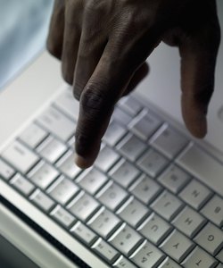 Man's hand above laptop computer, close-up, part of, selective focus