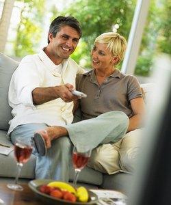 Couple sitting on sofa, man holding remote control, smiling