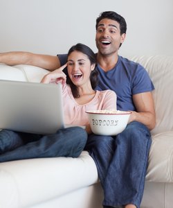 Portrait of a laughing couple watching a movie while eating popcorn