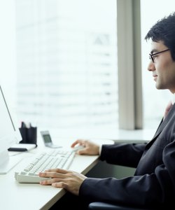 Businessman working on computer at desk in office, side view