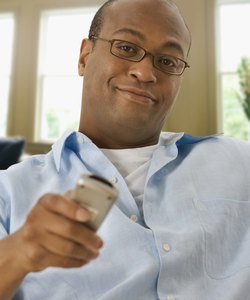 African man watching television with remote control