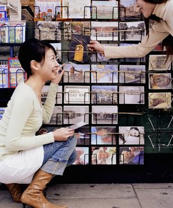 Two young women by souvenir stall, choosing postcards