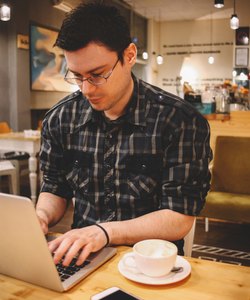 Young man sitting in a coffee shop using laptop
