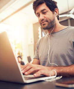 Caucasian man sitting in coffee shop using laptop
