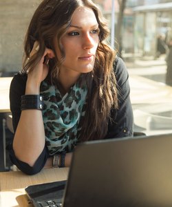 Beautiful Brunette Working on Laptop in a City Cafe