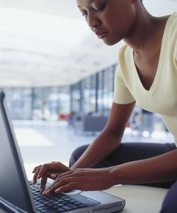 Side profile of a young woman working on a laptop