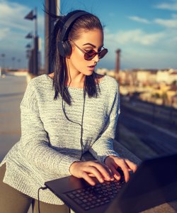 Young hipster woman typing on laptop outdoor