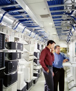 Two businessmen using computer in server room