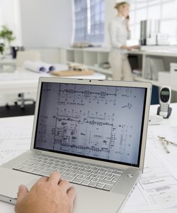 Blueprints on computer screen with businesswoman talking on cell phone