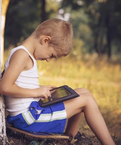 Boy Child playing with Tablet PC Outdoor