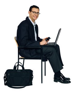 Businessman sitting on chair with laptop computer and cell phone