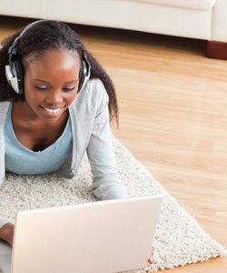 Close up of woman lying on floor with laptop listening to music