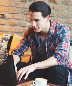 Young man sitting at a cafe, using a laptop