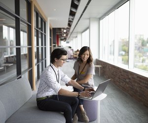 Businessman and businesswoman using laptop, meeting in office lounge
