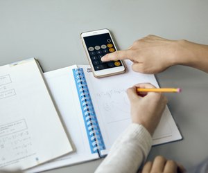 Students using smartphone calculator function while completing math assignment