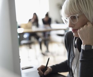 Focused female graphic designer using graphics tablet at computer