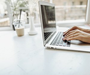 European hands typing on laptop keyabord on white table