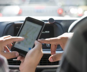 Cropped shot of hand tourists are searching for a way on the map in the application on car.