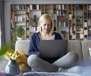 Woman at home sitting on couch using laptop