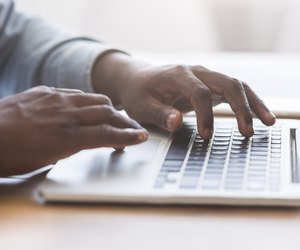 Unrecognizable african american man typing on laptop keyboard in office