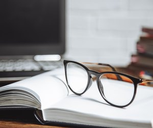 Eyeglasses on an open notebook on a wooden background.