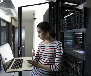 Female Filipino IT technician working at laptop in server room