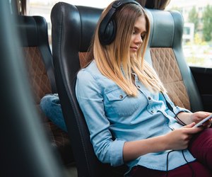 woman in headphones sleeping and listening music with smartphone during trip on travel bus