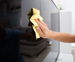 Woman Using Cloth To Clean The Television