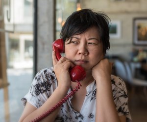 Serious Woman Talking On Telephone At Home