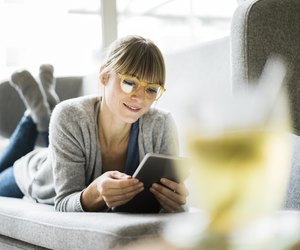 Smiling woman lying on couch using tablet