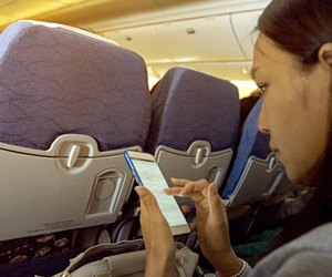 Side View Of Mid Adult Woman Using Mobile Phone While Sitting In Airplane