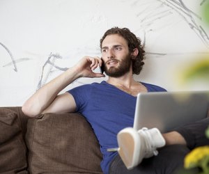 Portrait of young man on the phone sitting on couch in a coffee shop