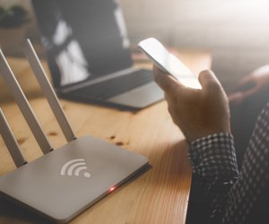 closeup of a wireless router and a man using smartphone on living room at home ofiice