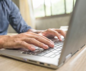 Businessman at a desk in an office typing on a laptop computer