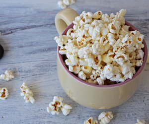 A bowl of delicious caramel popcorn on a white wooden background
