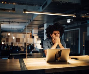 Tired businessman working on laptop at desk
