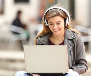Girl listening and downloading music from laptop