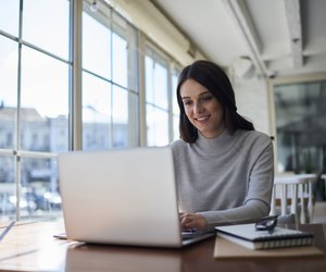 Smiling attractive female freelancer doing remote job using laptop computer