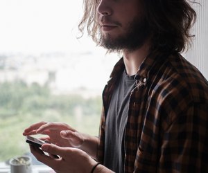 Young bearded man using phone at home