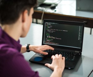 Young man using his laptop to try to solve problem with code