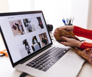 Close-up of fashion designer in studio with laptop examining fabric